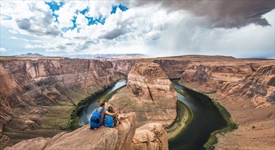 Young couple sitting on a rock and looking over the Horseshoe Bend