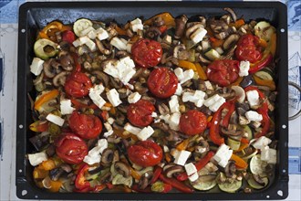 Roasted vegetables with feta cheese on a baking tray