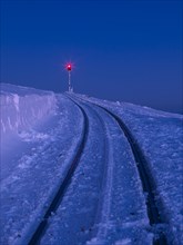 Red signal light on snow-covered tracks of the Brocken railway