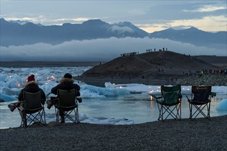 Tourists in camping chairs waiting for fireworks at the glacier lagoon Jokulsarlon
