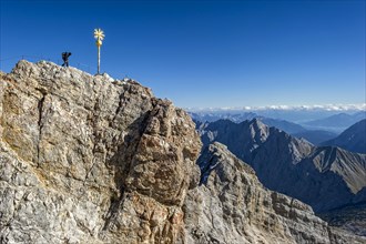 Mountaineer at the summit cross of the Zugspitze