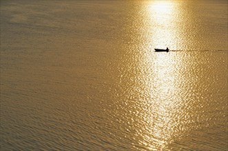 Fisherman in a motorboat at sunset