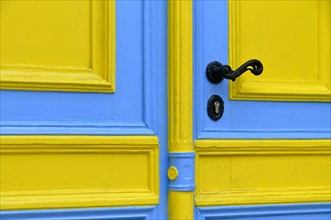 Blue and yellow painted front door with a black doorknob