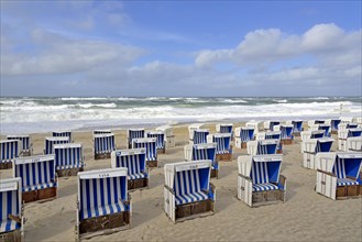 Sandy beach beach of Westerland with white-blue beach chairs at stormy North Sea