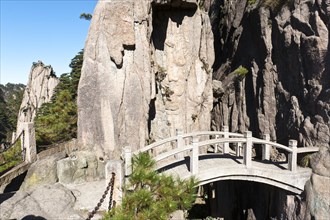 Small arch bridge spanning deep canyon of granite rocks