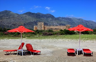Red sun loungers and parasols in front of Frangokastello castle