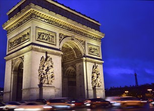 Illuminated Arc de Triomphe with traffic at night