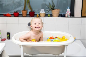 Toddler bathing in a bathtub for children with rubber ducks