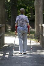 Elderly woman walking with crutches
