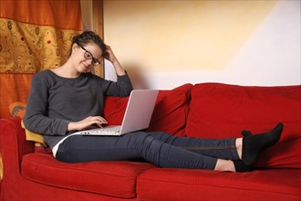 Teenager sitting with a laptop on a couch