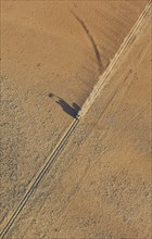 A vehicle of the balloon ground crew crosses a sandy plain