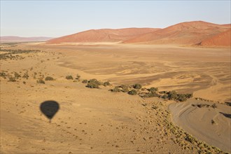 Shadow of the hot-air balloon over an arid plain and the dry riverbed of the Tsauchab river at the edge of the Namib Desert