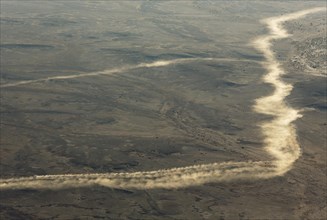 Dust trails left by vehicles driving on gravel roads at the edge of the Namib Desert