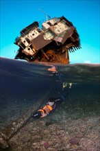 Freediver swims with underwater scooter near a shipwreck