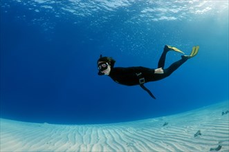 Freediver diving above a sandy bottom