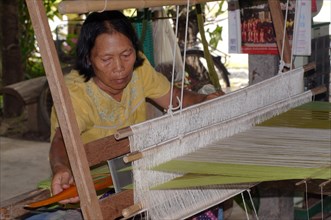 An elderly Tai Dam woman working on an old wooden loom