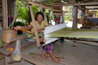 An elderly Tai Dam woman working on an old wooden loom