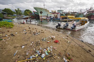 Fishing boats and beach with trash at the port of Ambon-Laha