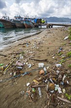 Fishing boats and beach with trash at the port of Ambon-Laha