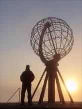 Man next to the globe at the North Cape platform Nordkapplataet