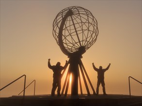 Two men next to the globe at the North Cape platform Nordkapplataet