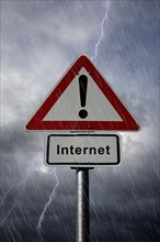Warning and Internet road signs againt a rainy sky with lightning