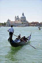 Gondola and gondolier with tourists in front of the church of Santa Maria della Salute
