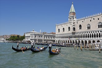Gondolas with tourists and gondoliers in front of Palazzo della Zecca and the Palazzo Ducale