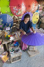 A woman is painting parasols at the umbrella village of Bo Sang