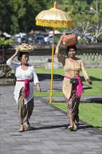 Women in traditional dress carrying basket with offerings on their heads