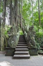 Two stone dragon statues guarding the stairs at the holy bathing pool of Pura Dalem Agung Padangtegal or Monkey Forest Temple
