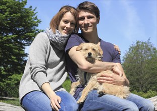 Happy young couple holding a Terrier mixed-breed dog