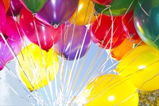 Colourful helium-filled balloons against a blue sky