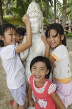Chinese girls laughing by a Buddha statue on the beach by Dongjiao Yelin