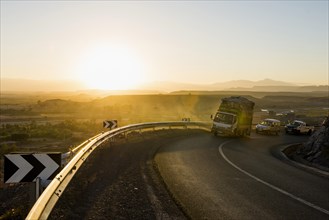 Loaded truck on curvy road in Dades Valley at sunset