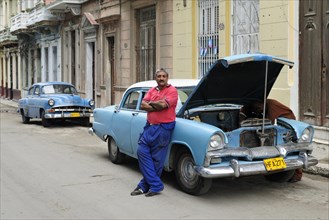 Man next to American classic car being repaired in the streets