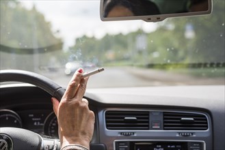 Woman's hand with cigarette at the wheel