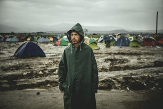 Man waiting outside tents in heavy rain