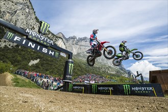Two motorcyclists on motocross bikes jumping through the air