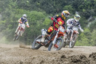 Group of motorcyclists on motocross bikes riding on a dirt track