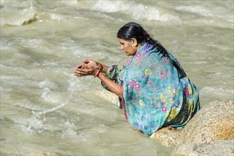 A female pilgrim at the banks of the river Ganges is praying