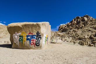 A big Tibetan Mani Stone with the Mantra "Om Mani Padme Hum" colorfully engraved on a hill above the Indus Valley