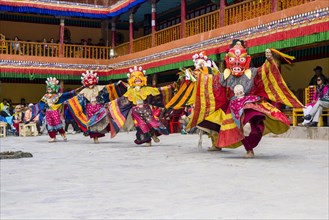Monks with big wooden masks and colorful costumes are performing ritual dances at Hemis Festival in the courtyard of the monastery