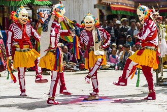 Monks with big wooden masks and colorful costumes are performing ritual dances at Hemis Festival in the courtyard of the monastery