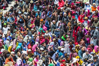 Large crowds of locals und tourists are watching monks with big wooden masks and colorful costumes performing ritual dances at Hemis Festival in the courtyard of the monastery