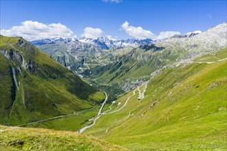 Road leading to Furka Pass winding up a green mountain slope
