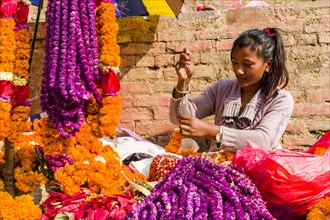 A young woman is arranging flowers on the flowermarket at Durbar Square