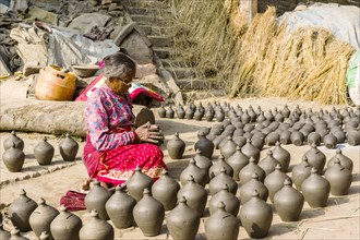 A woman is working at pottery in the streets