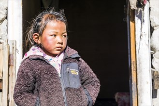 Portrait of a little boy standing in front of a door