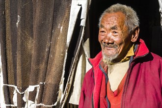 Portrait of an old monk in front of a door of the Thame Gompa monastery